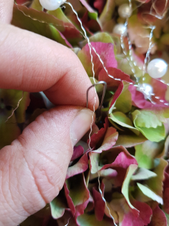 Der Silberdraht wird mit den dünnen Draht-Agraffen fixiert. Der Bogen vom Draht, wird mit einer Hortensienblüte überdeckt.